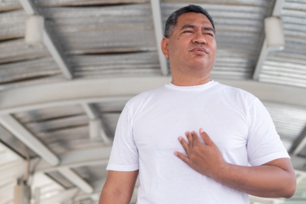 A man clutches his chest as he experiences heartburn. 